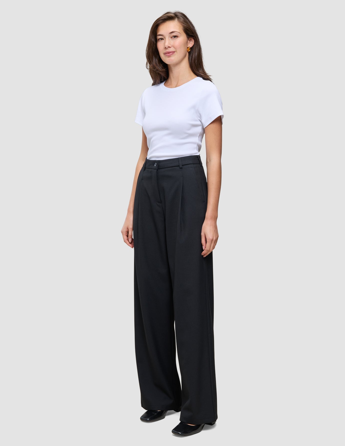 Kvinna klädd i en vit t-shirt och svarta Serene Pants Wide med hög midja.